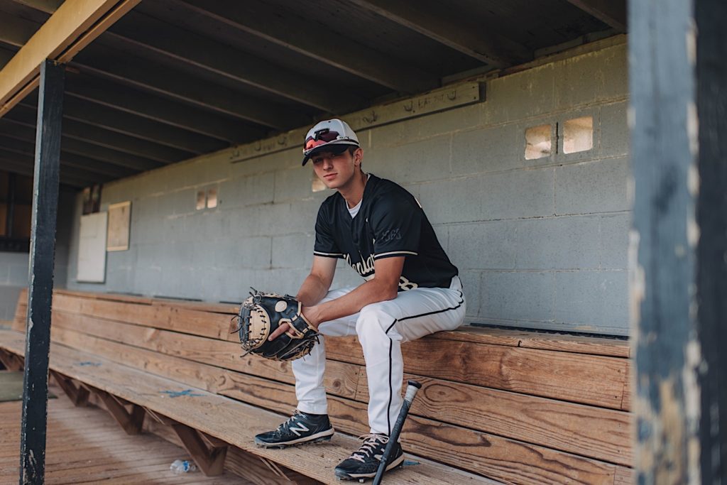 Senior portrait in baseball dugout 