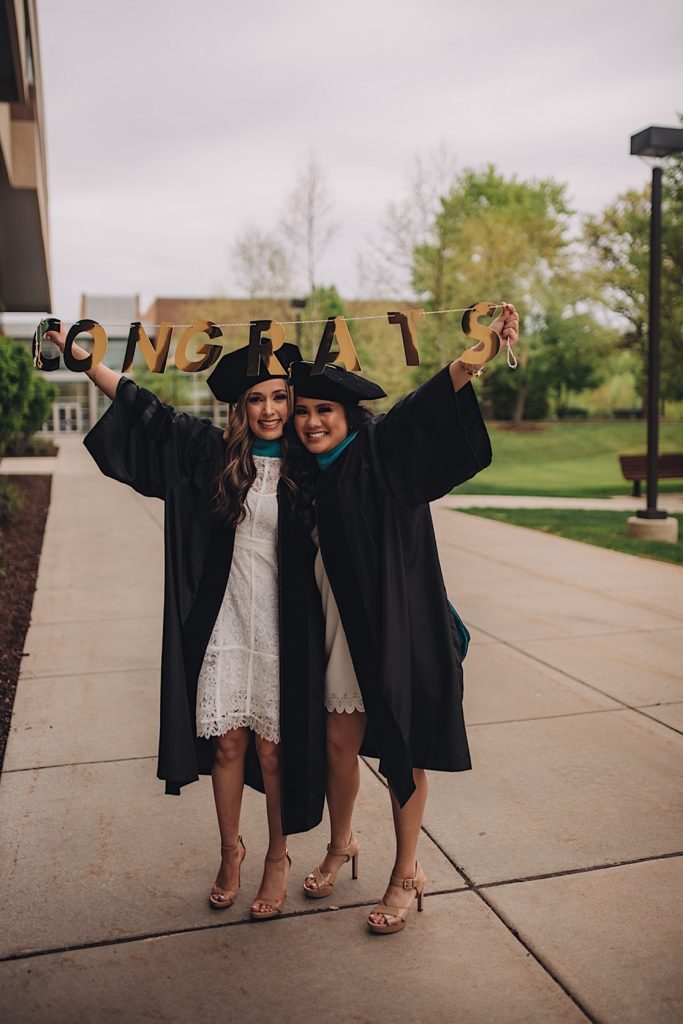 Grads holding sign celebrating their graduation during friendship session